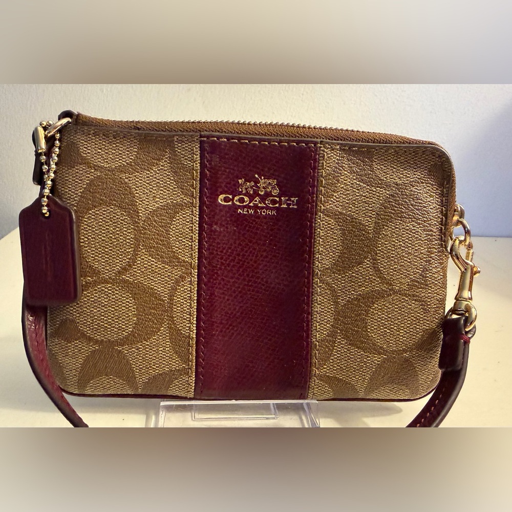 Coach wristlet signature pattern with burgundy trim.